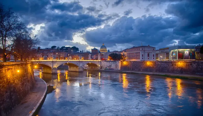 Il Tevere riflette le luci di Roma al tramonto, un'atmosfera magica per decidere cosa fare il sabato sera a Roma.