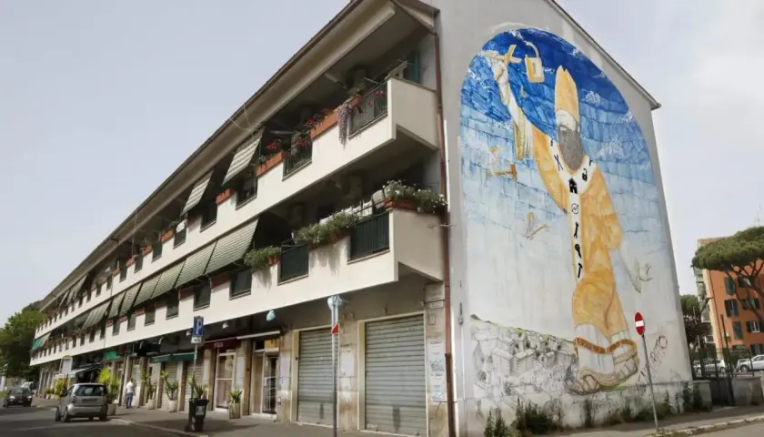 San Basilio, Roma: un imponente murale raffigurante San Basilio con simboli di protezione e cura, adorna un edificio residenziale.