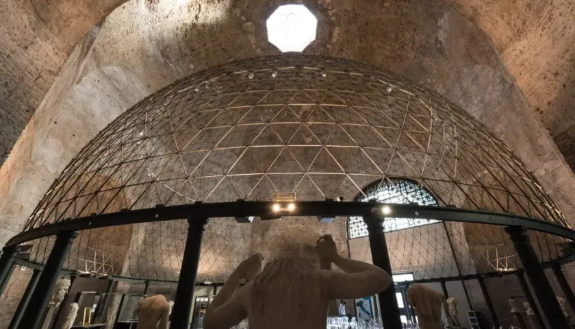 Interno di un'aula ottagona con cupola geodetica e sculture antiche. Luce zenitale illumina l'ambiente.