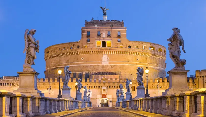 Ponte Sant'Angelo illuminato di sera, con le statue degli angeli e Castel Sant'Angelo sullo sfondo. Curiosità: la statua in cima al castello.
