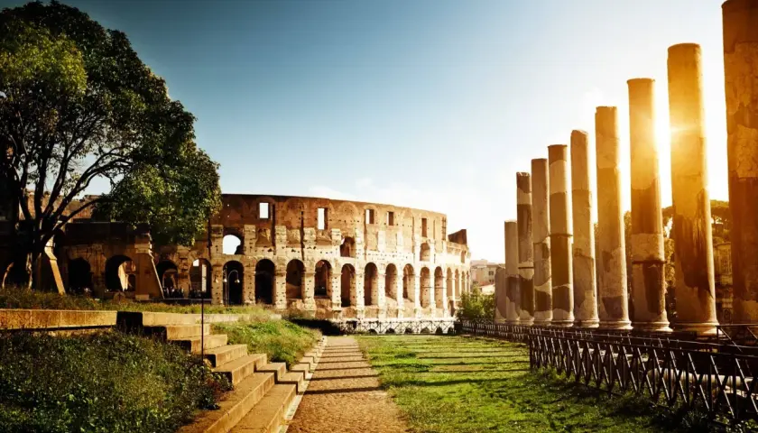 Il Colosseo e le colonne antiche, un'icona tra le 20 cose da vedere a Roma, illuminate dal sole del tramonto.