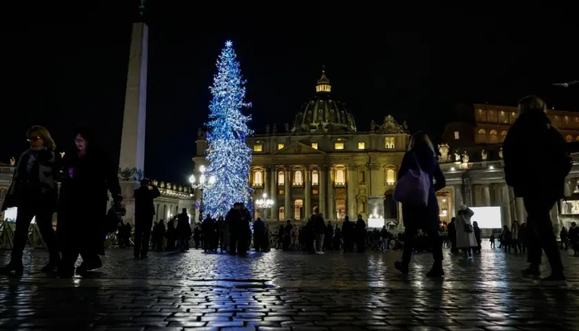 Piazza San Pietro illuminata da un grande albero di Natale blu, con gente che passeggia. Un'idea su cosa fare il 24 dicembre a Roma.