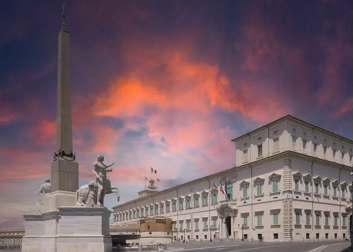 Il Quirinale, Colle Romano, con obelisco e scultura equestre sotto un cielo infuocato.