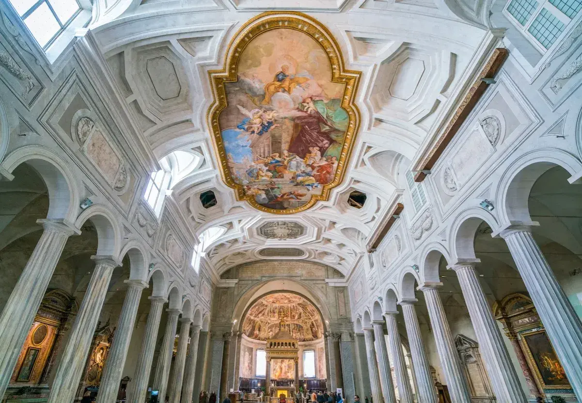 Interno della Basilica di San Pietro, con affreschi sul soffitto e colonne imponenti.