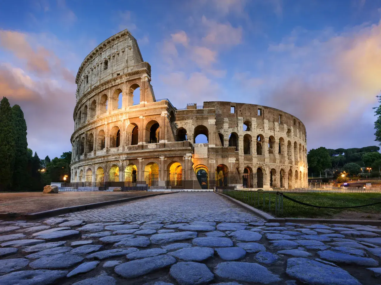 Il Colosseo, uno dei più maestosi monumenti di Roma, illuminato al tramonto con un cielo suggestivo.