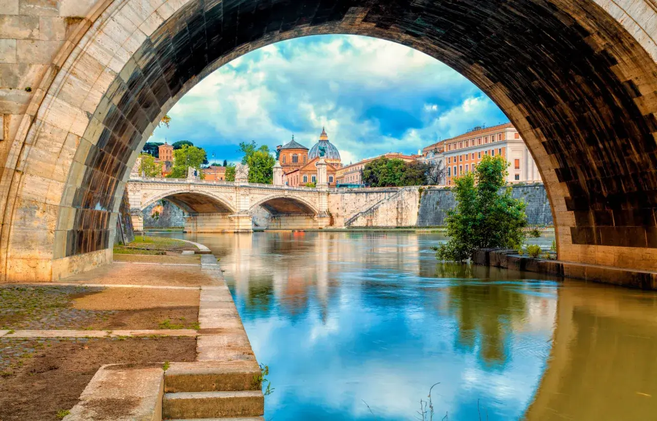 Ponte Sant'Angelo e il Tevere, un'icona di cosa vedere a Roma. La cupola di San Pietro si riflette sull'acqua.