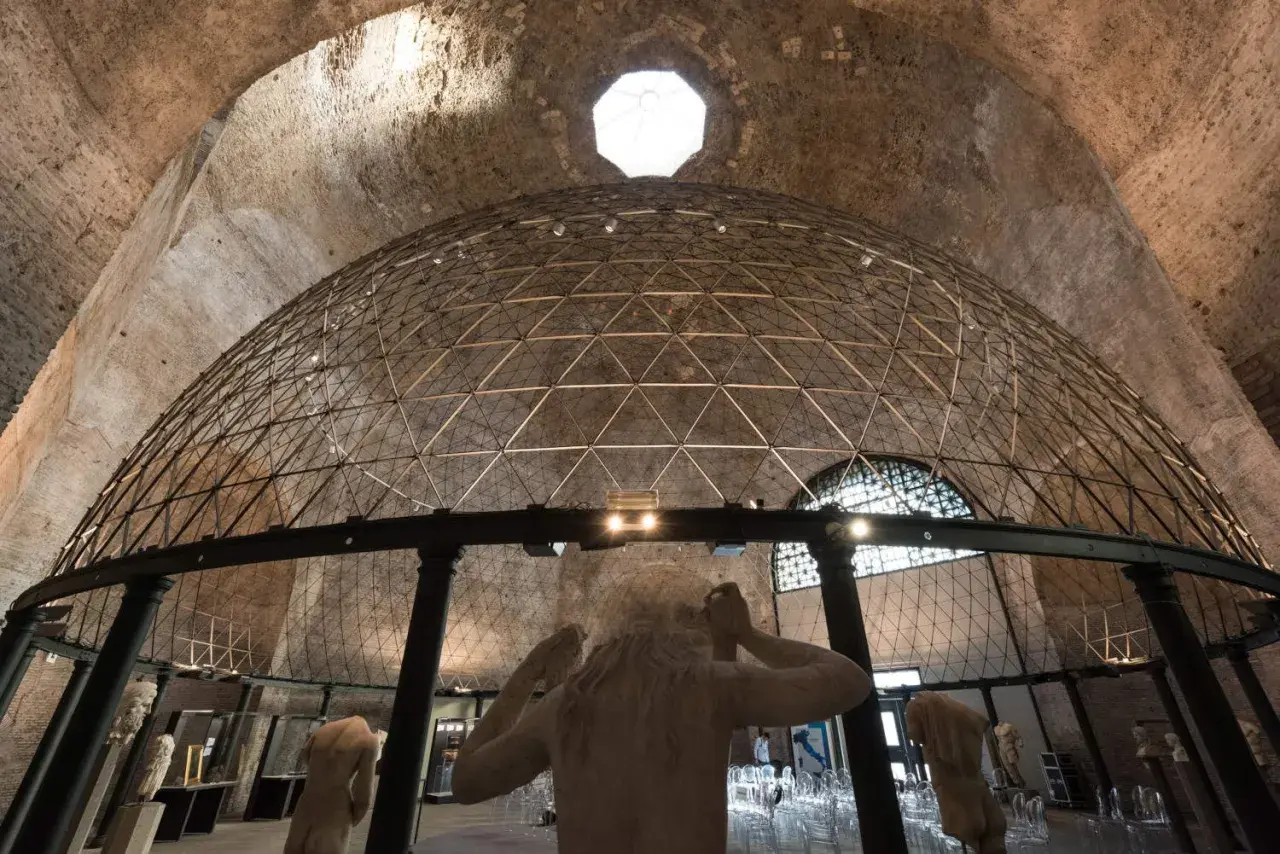Interno di un'aula ottagona con cupola geodetica e sculture antiche. Luce zenitale illumina l'ambiente.