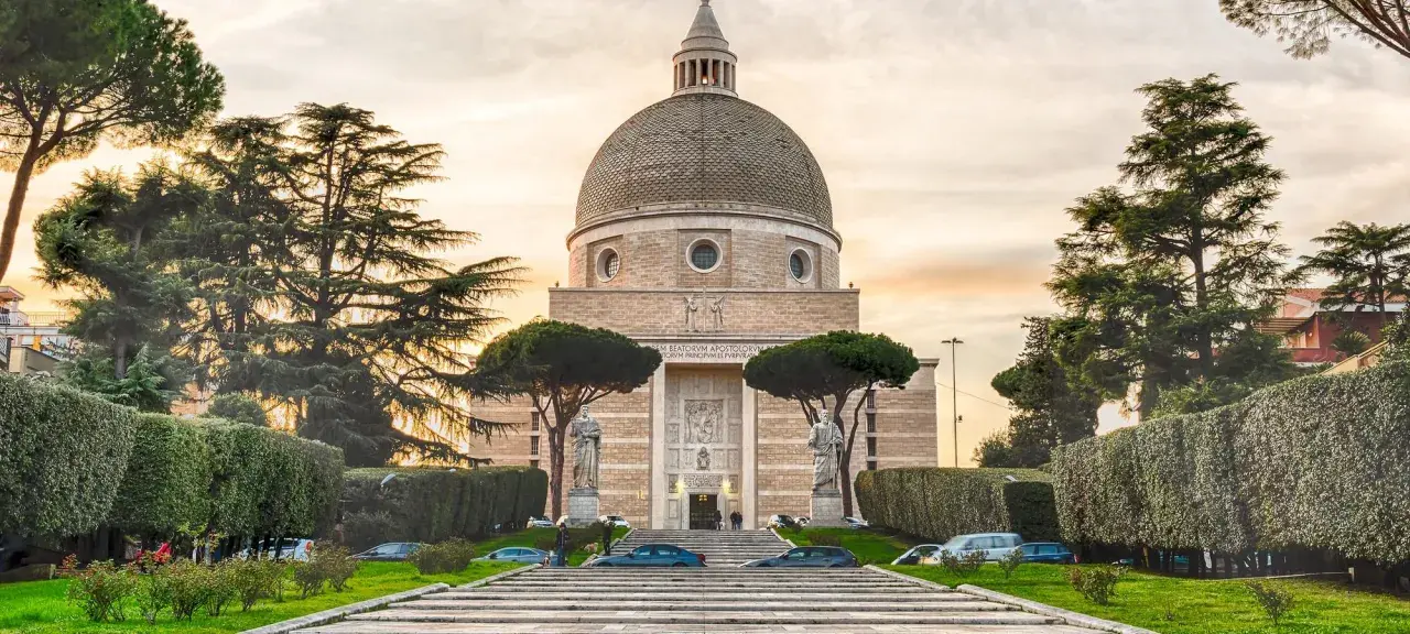 Basilica di San Pietro e Paolo a Roma, con la sua imponente cupola e statue, circondata da alberi e giardini curati.