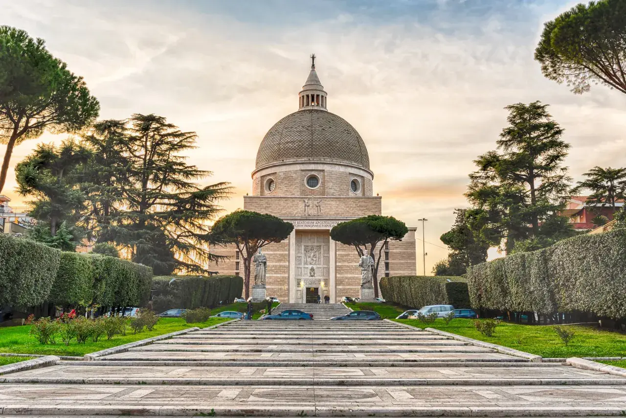La Basilica dei Santi Pietro e Paolo a Roma, con la sua imponente cupola, si erge maestosa tra alberi secolari e giardini curati.