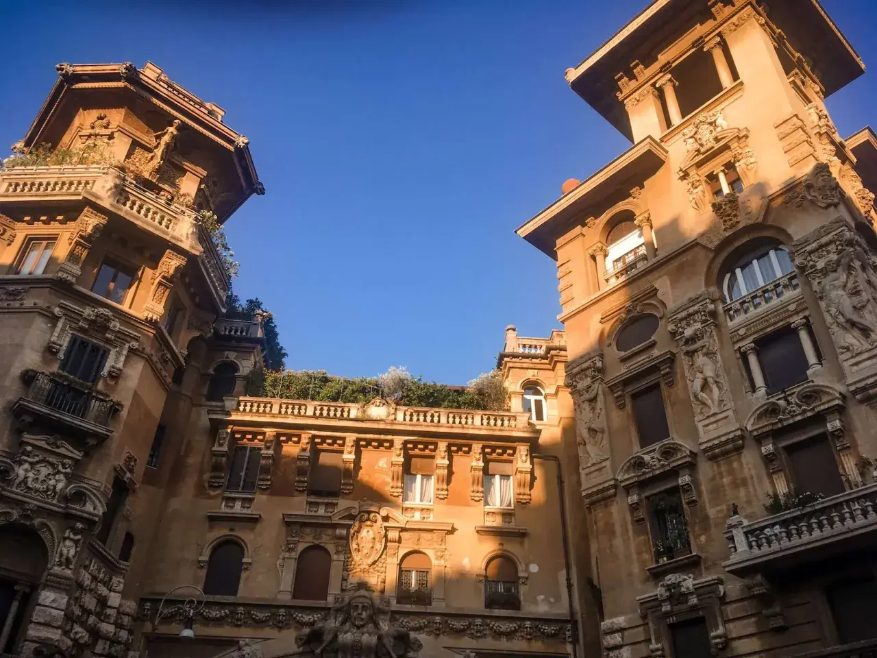 Edifici in stile liberty a Roma, con dettagli architettonici ricchi e un cielo azzurro intenso.
