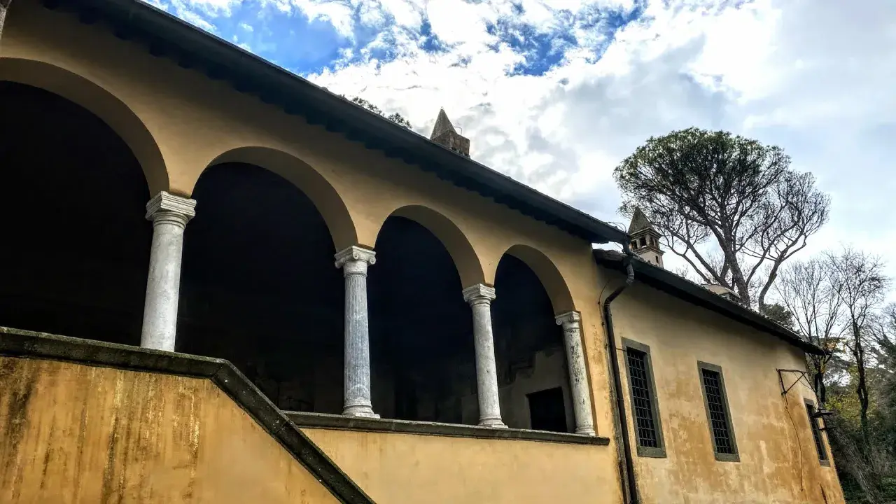 Portico con archi e colonne di marmo della casina cardinal Bessarione, con un grande albero sullo sfondo.