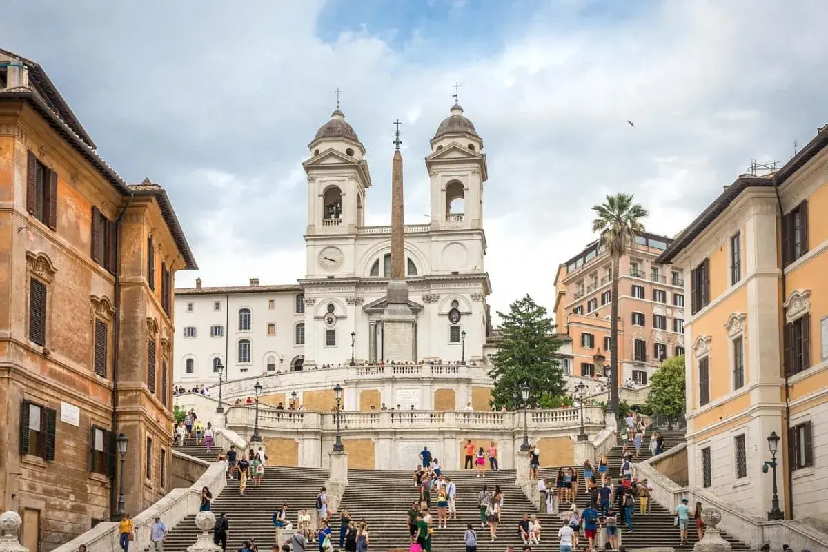 Scalinata di Trinità dei Monti, un must per chi cerca cosa vedere a Roma in una settimana. Turisti salgono i gradini verso la chiesa con obelisco.