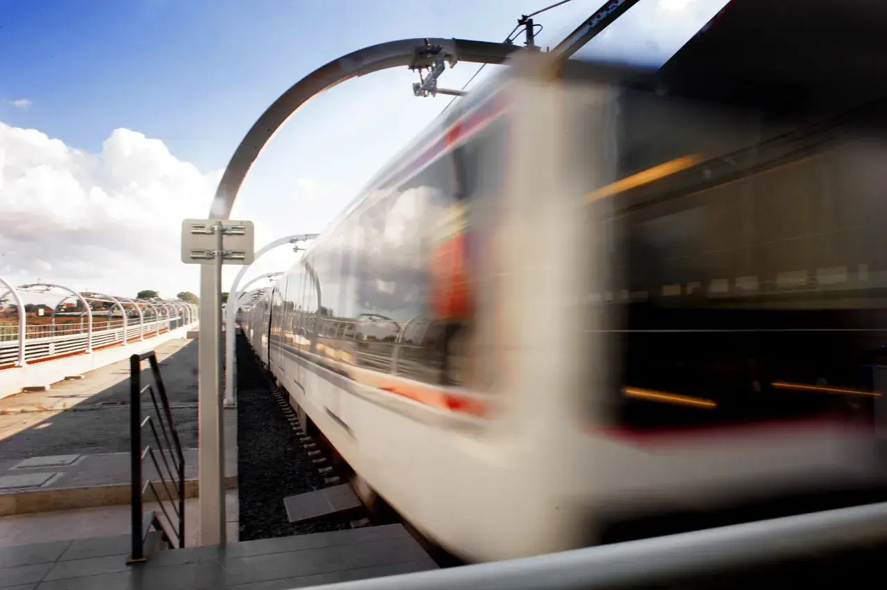 Treno in corsa sulla borghesiana metro c, con riflessi nel cielo e luci interne.