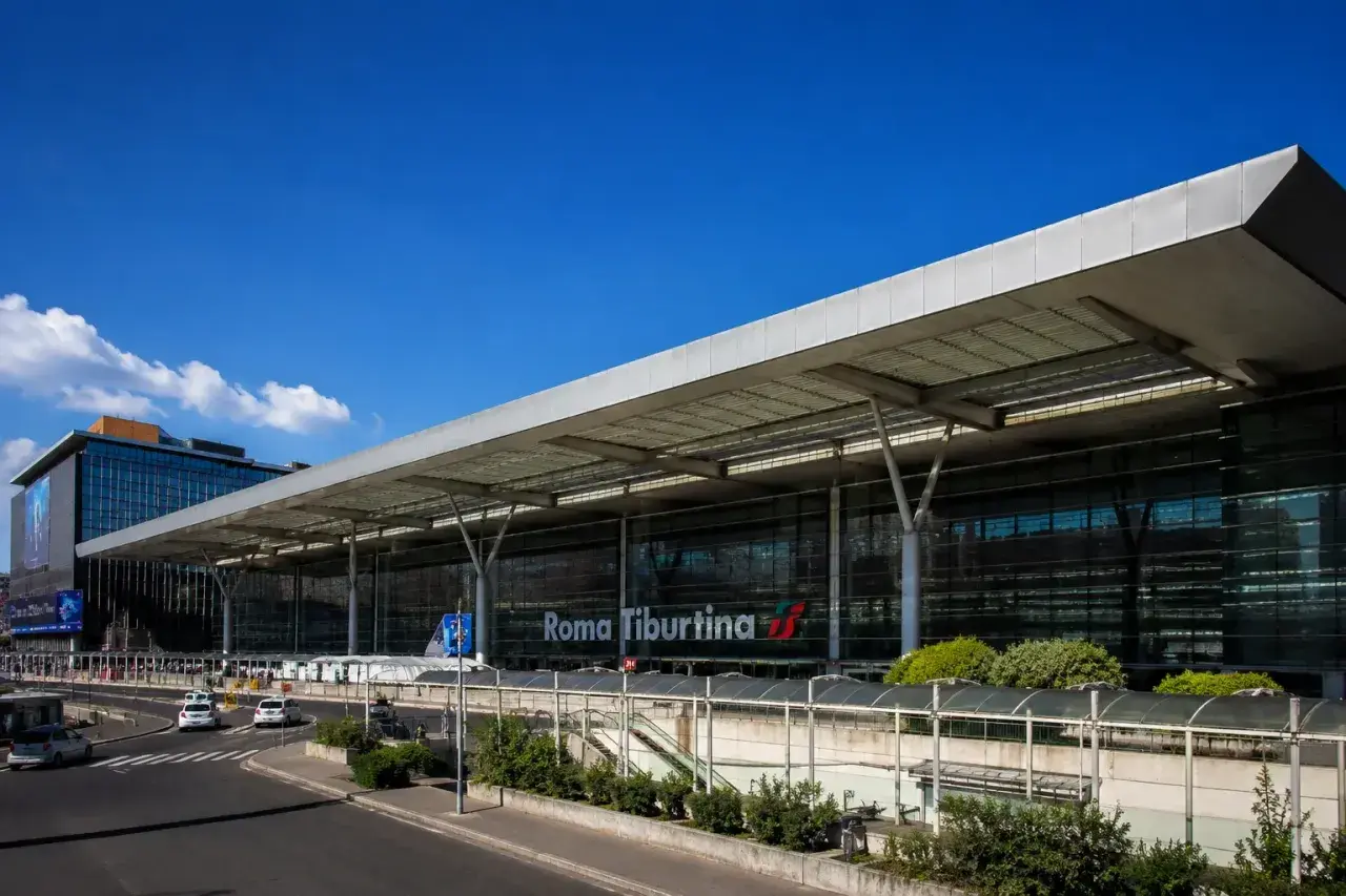 La moderna stazione di Roma Tiburtina, con la sua architettura in vetro e acciaio, accoglie viaggiatori diretti verso la metropolitana e oltre.