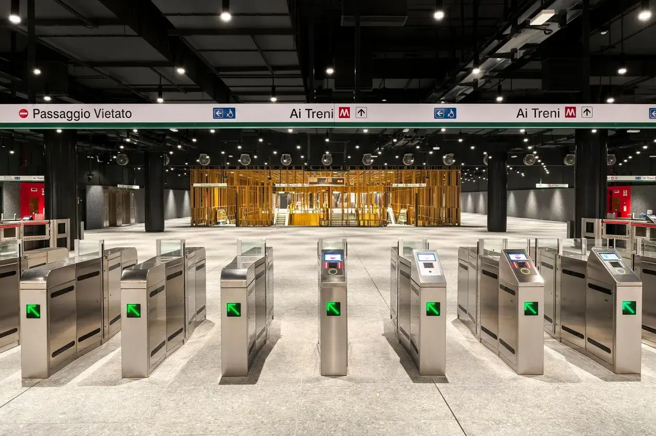 Cancelli automatici di una moderna stazione metro a Roma, con indicazioni per le fermate e i treni.