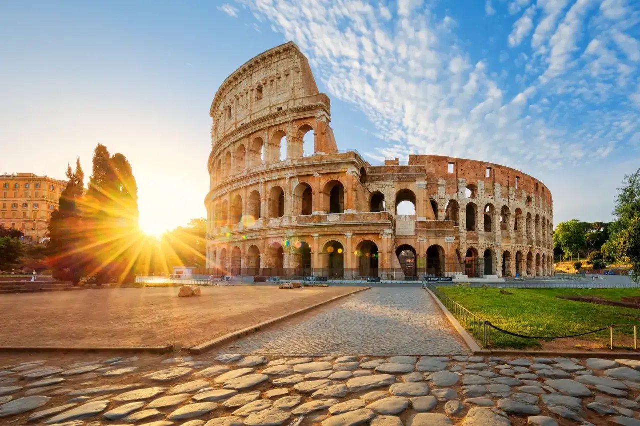 Il Colosseo all'alba, con i raggi del sole che illuminano l'anfiteatro. Vicino alla fermata metro Colosseo, linea B.