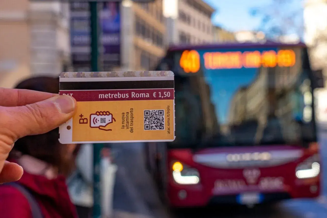 Un biglietto Metrebus Roma da 1,50€, la nuova vitamina del trasporto, pronto per essere usato su un bus rosso in città.