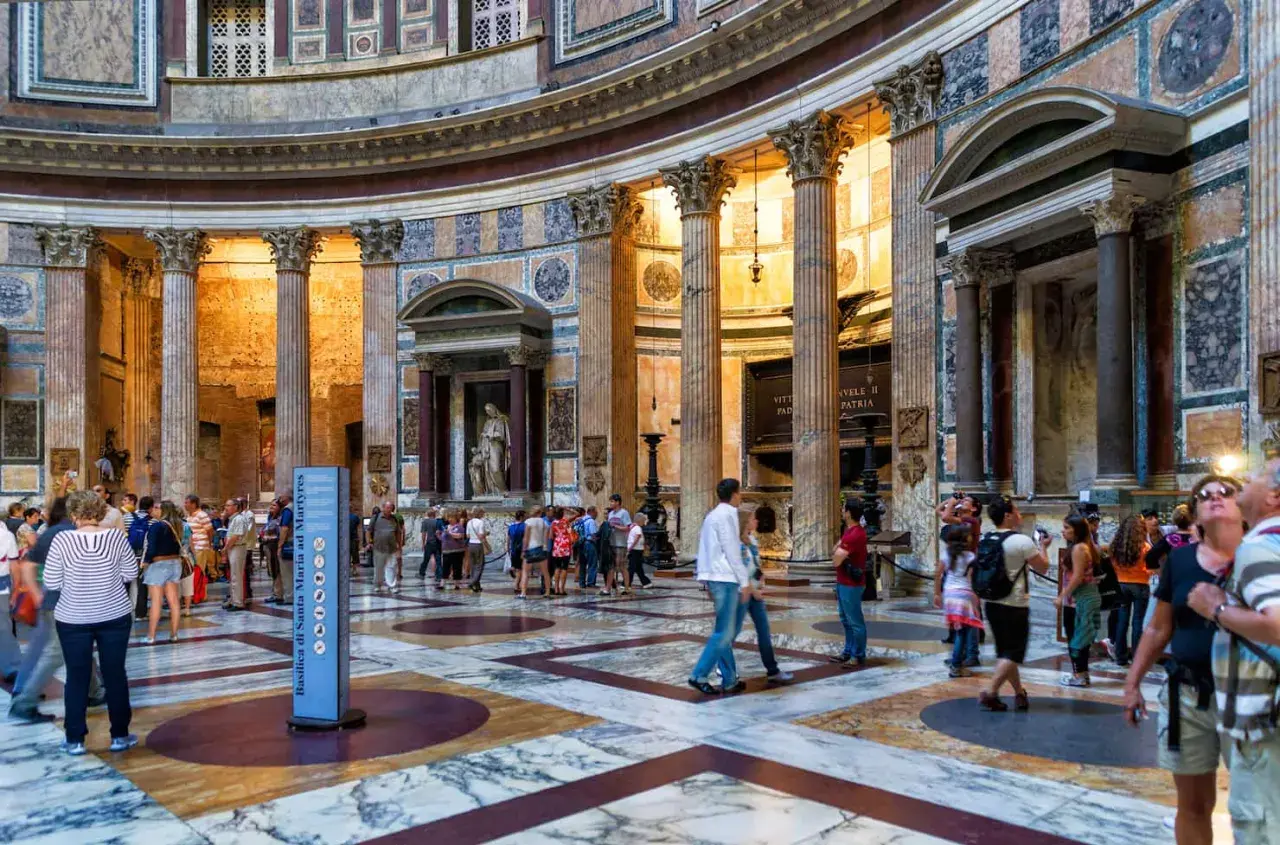 Interno del Pantheon a Roma, con turisti che ammirano la maestosa architettura e le colonne. La Piazza della Rotonda è un luogo iconico.