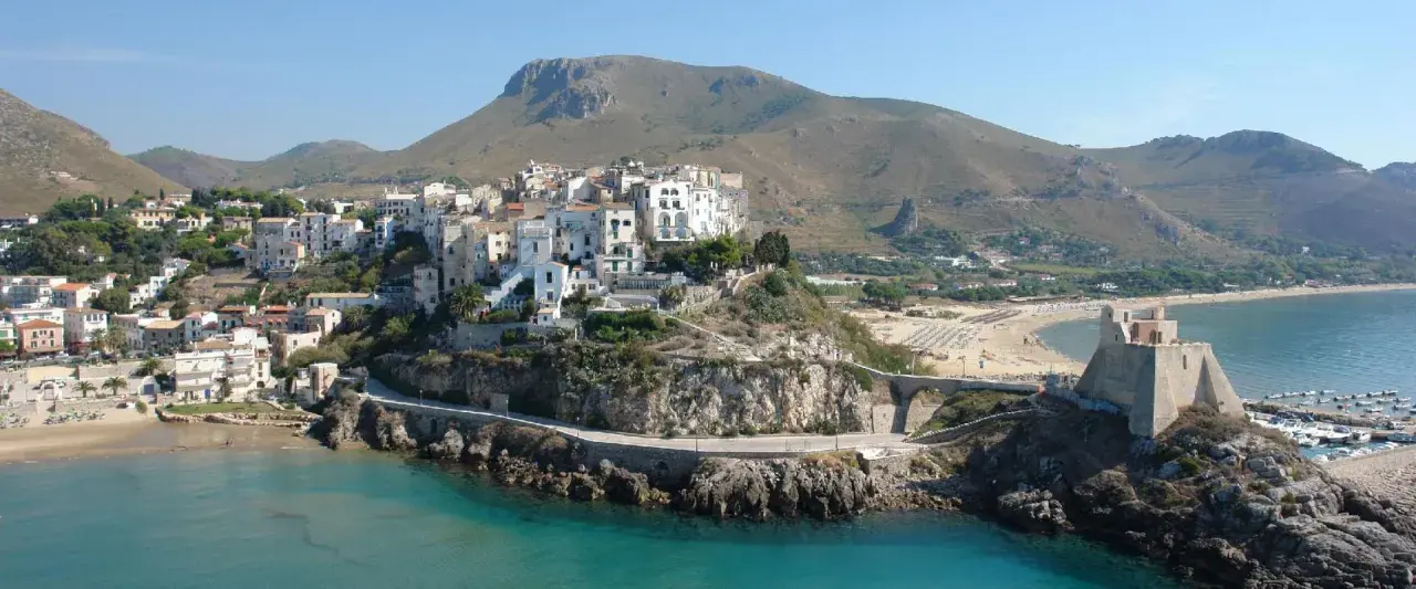 Panoramica di Sperlonga: cosa vedere tra il borgo bianco arroccato, la spiaggia dorata e l'antica torre sul promontorio roccioso.