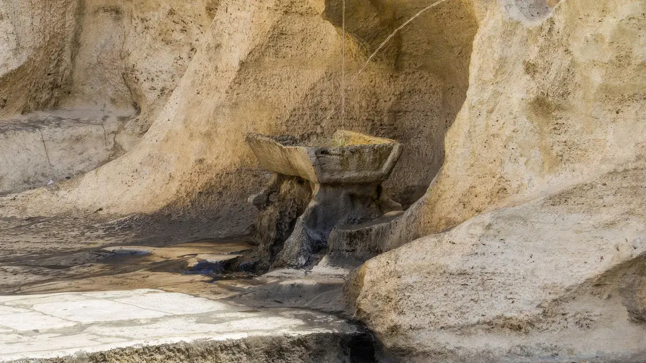 Antica fontana degli innamorati a Roma, scolpita nella roccia, con acqua che scorre.