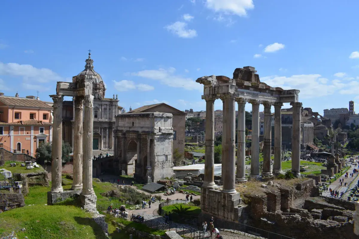 Le rovine del Foro Romano, con colonne imponenti e un arco trionfale, sotto un cielo azzurro. Un assaggio di Roma 72h.