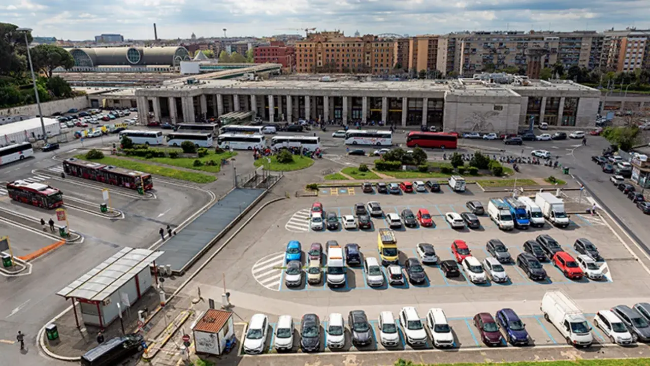 Ampio parcheggio di autobus e auto vicino alla stazione metro di Roma. Molti mezzi di trasporto pubblico e privato in un'area trafficata.