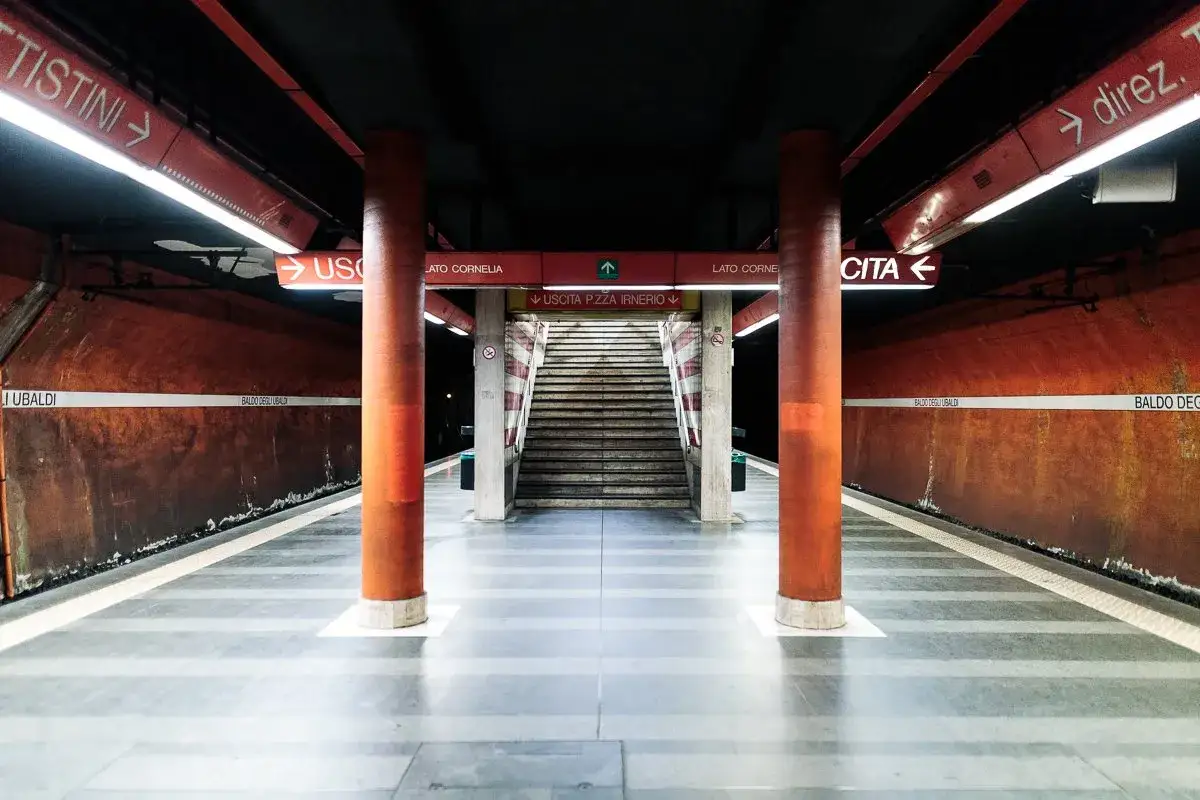 Stazione metro Baldo degli Ubaldi, con colonne arancioni, scale e indicazioni luminose.