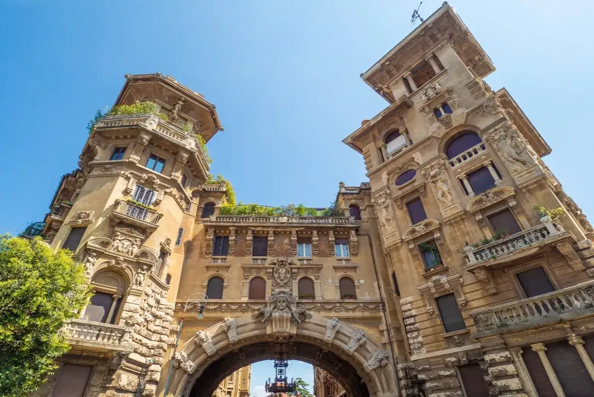 Edifici in stile liberty a Roma, con un arco imponente e dettagli architettonici elaborati sotto un cielo azzurro.