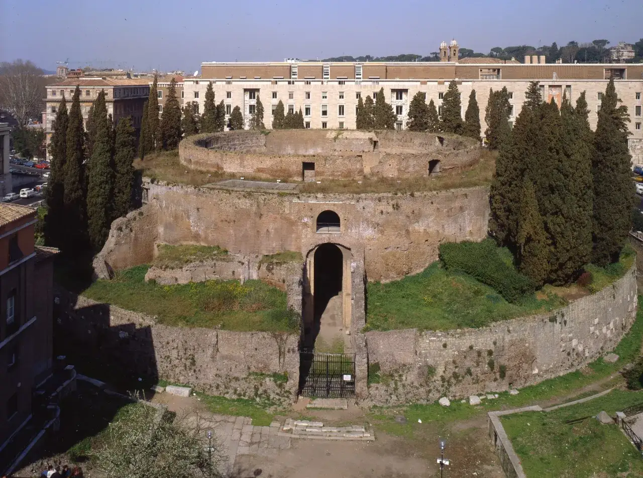 Antico mausoleo circolare a Roma, con un imponente arco d'ingresso e cipressi che lo circondano.