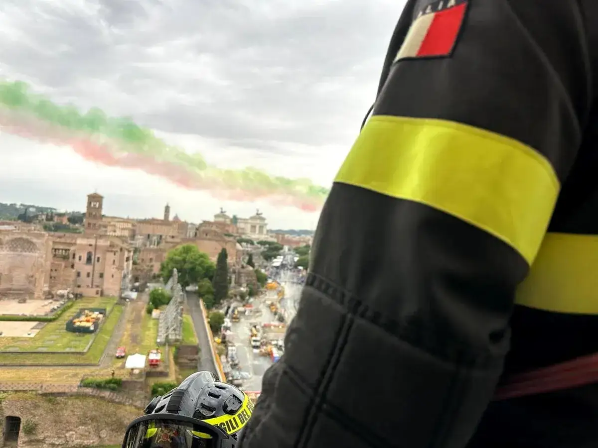 Frecce Tricolori sorvolano Roma il 2 giugno, con un vigile del fuoco che osserva la parata.