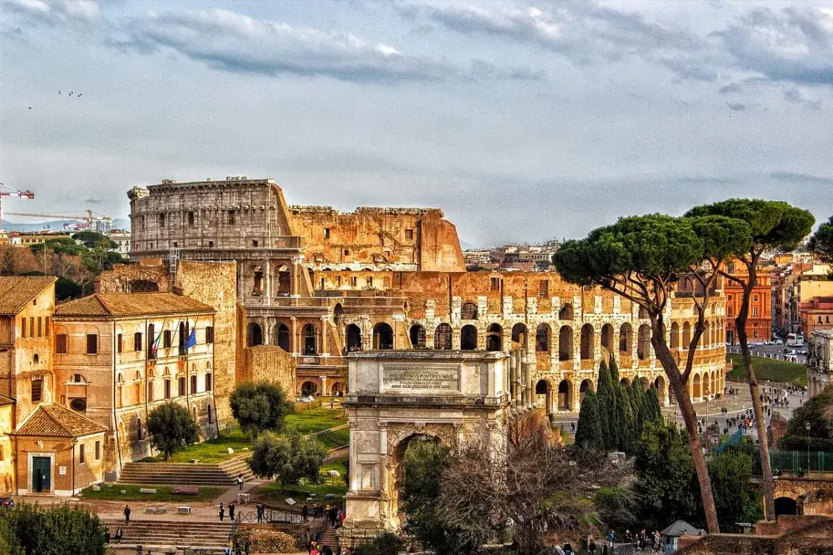 Un pomeriggio a Roma: il Colosseo e l'Arco di Tito visti da un punto panoramico, con pini marittimi e turisti.