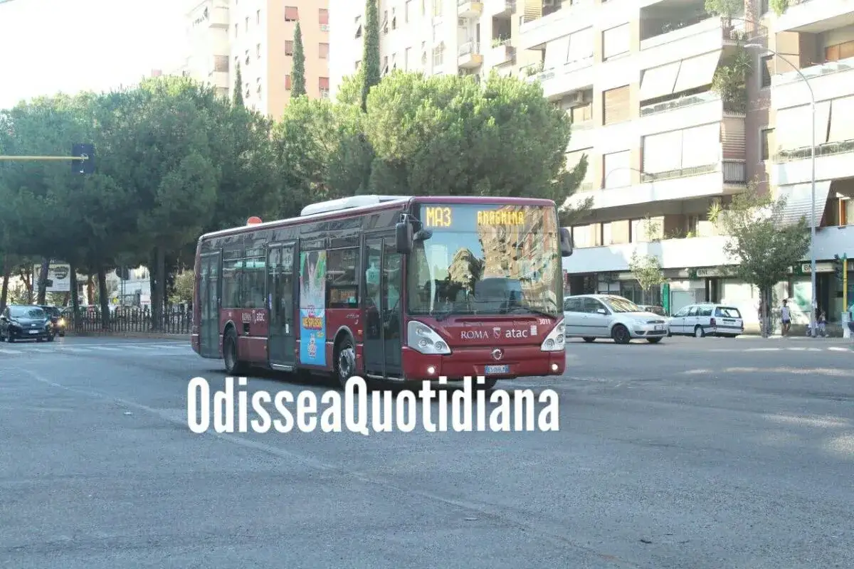 Un bus sostitutivo della metro MA3 ad Anagnina a Roma, in una giornata di sole, attraversa la strada tra alberi e palazzi.