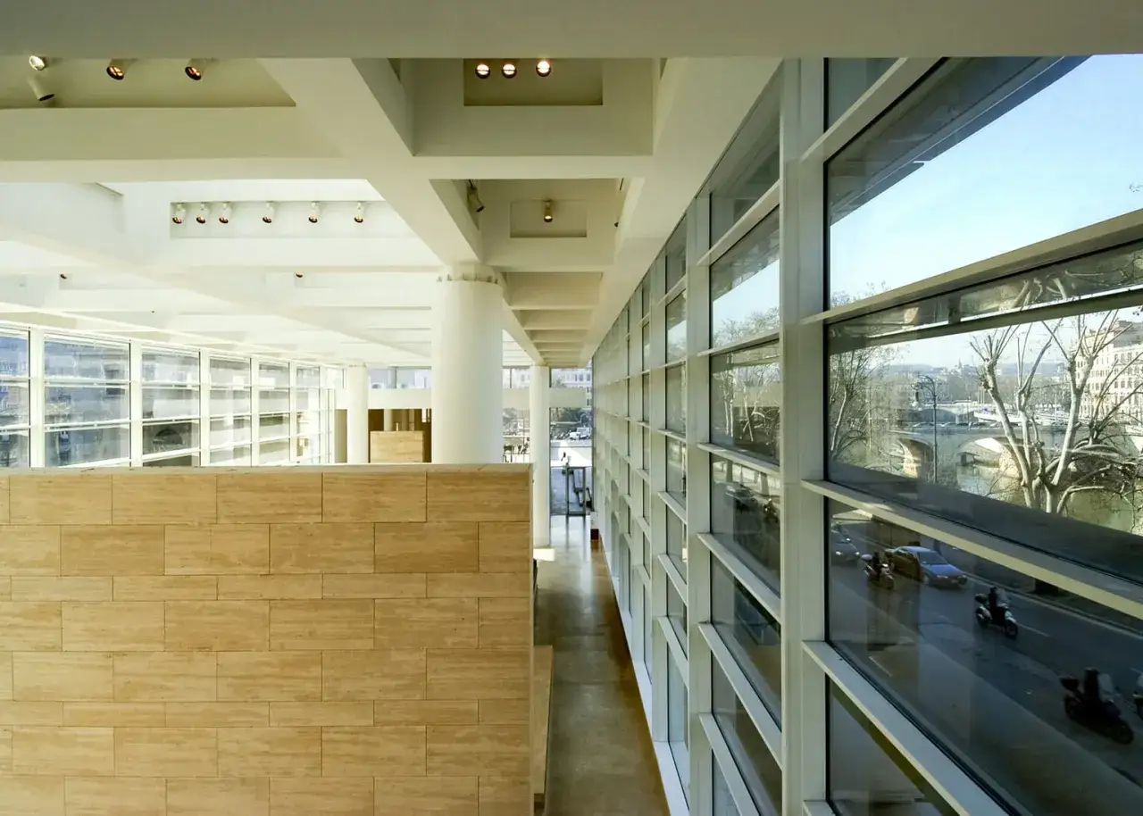Interno moderno con muro in travertino e vista su Roma, con il Ponte Sant'Angelo e l'Ara Pacis Meier in lontananza.