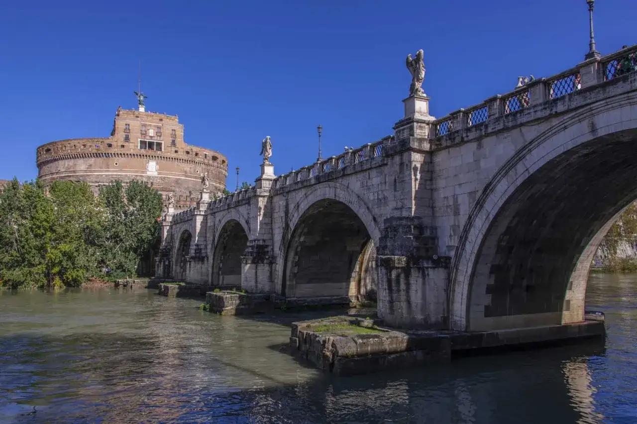 Ponte Sant'Angelo a Roma, con Castel Sant'Angelo sullo sfondo e statue di angeli che sorvegliano il Tevere.