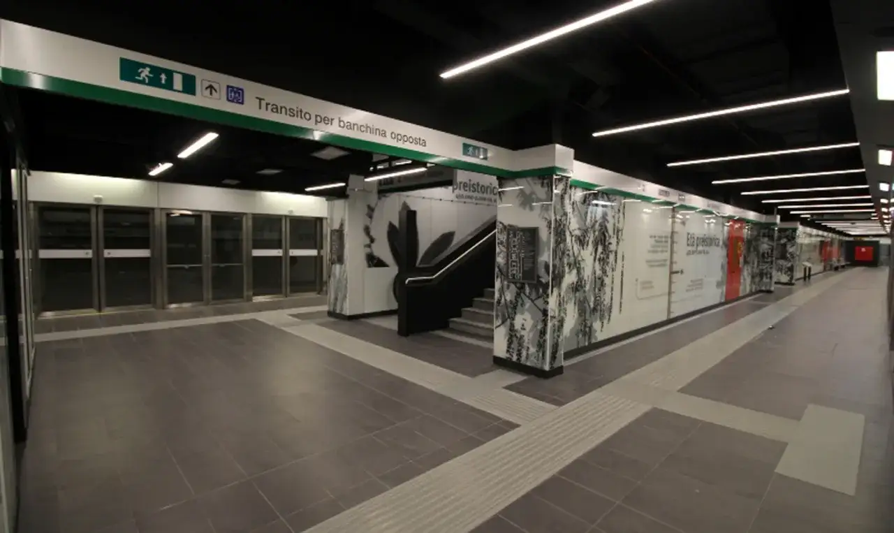 Stazione metro C San Giovanni, con indicazioni per il collegamento alla metro A. Pareti decorate con motivi naturalistici e scale mobili.