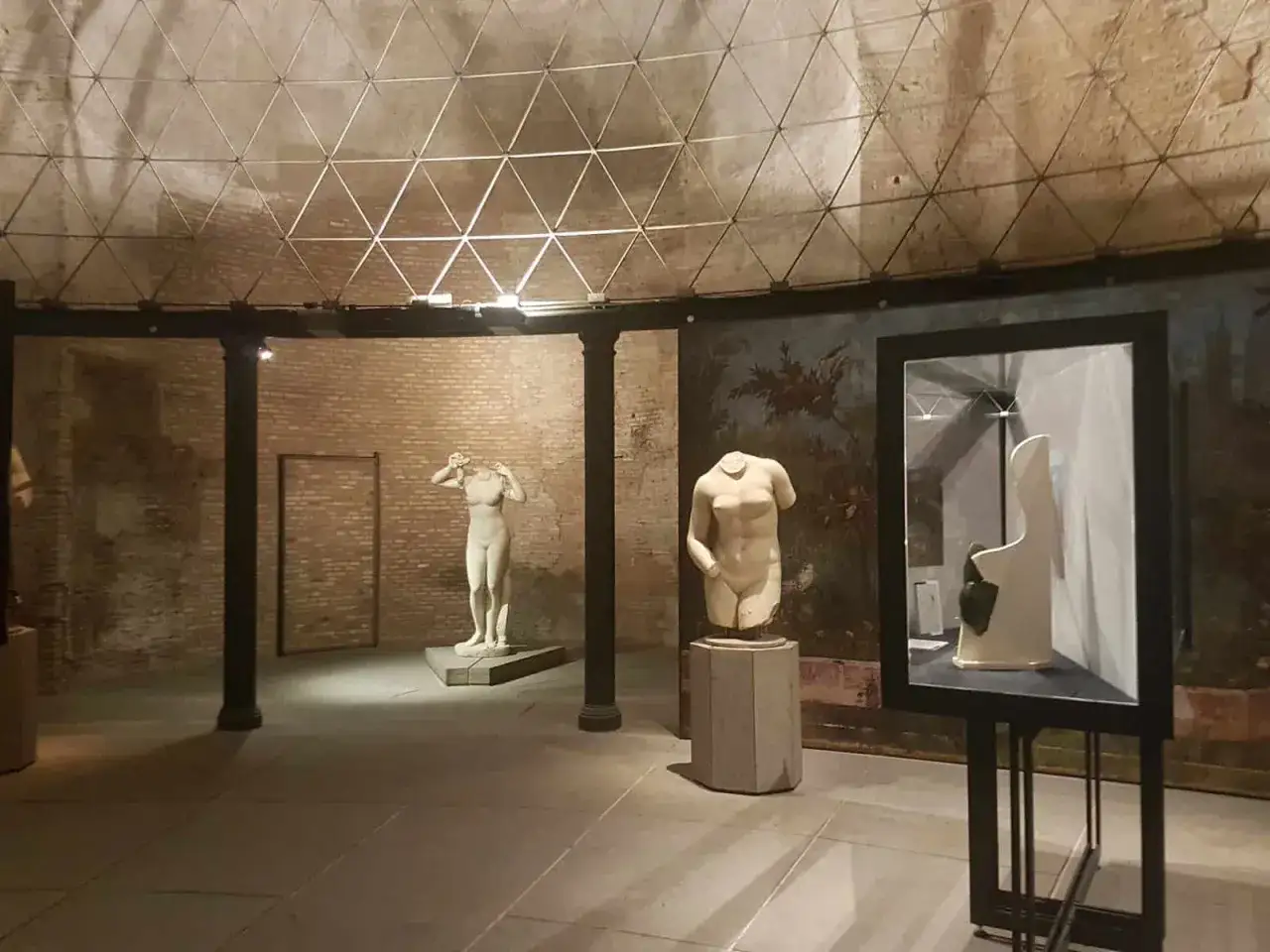 All'interno di un'aula ottagona, statue classiche e un busto di marmo sono esposti sotto una cupola a griglia.