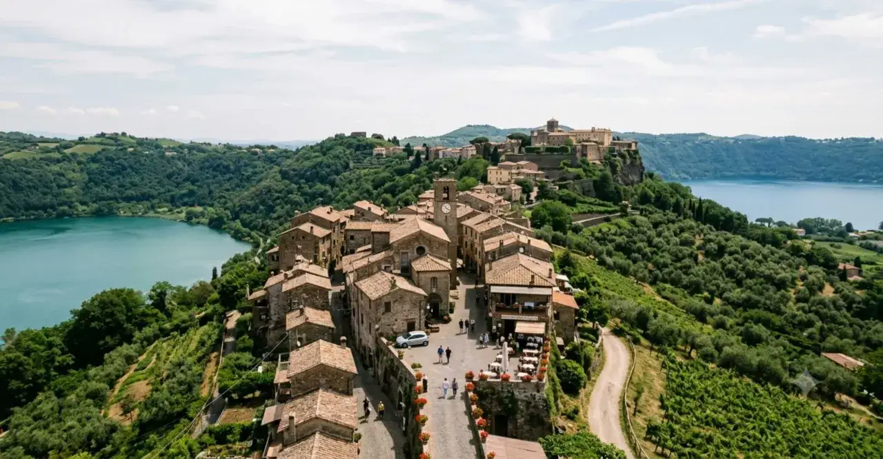 Un borgo medievale sui colli romani, con case in pietra, un lago azzurro e uliveti rigogliosi.