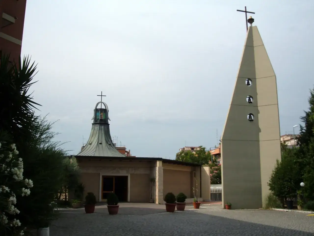 Chiesa moderna a San Basilio, Roma, con campanile a forma piramidale e tetto a cono.