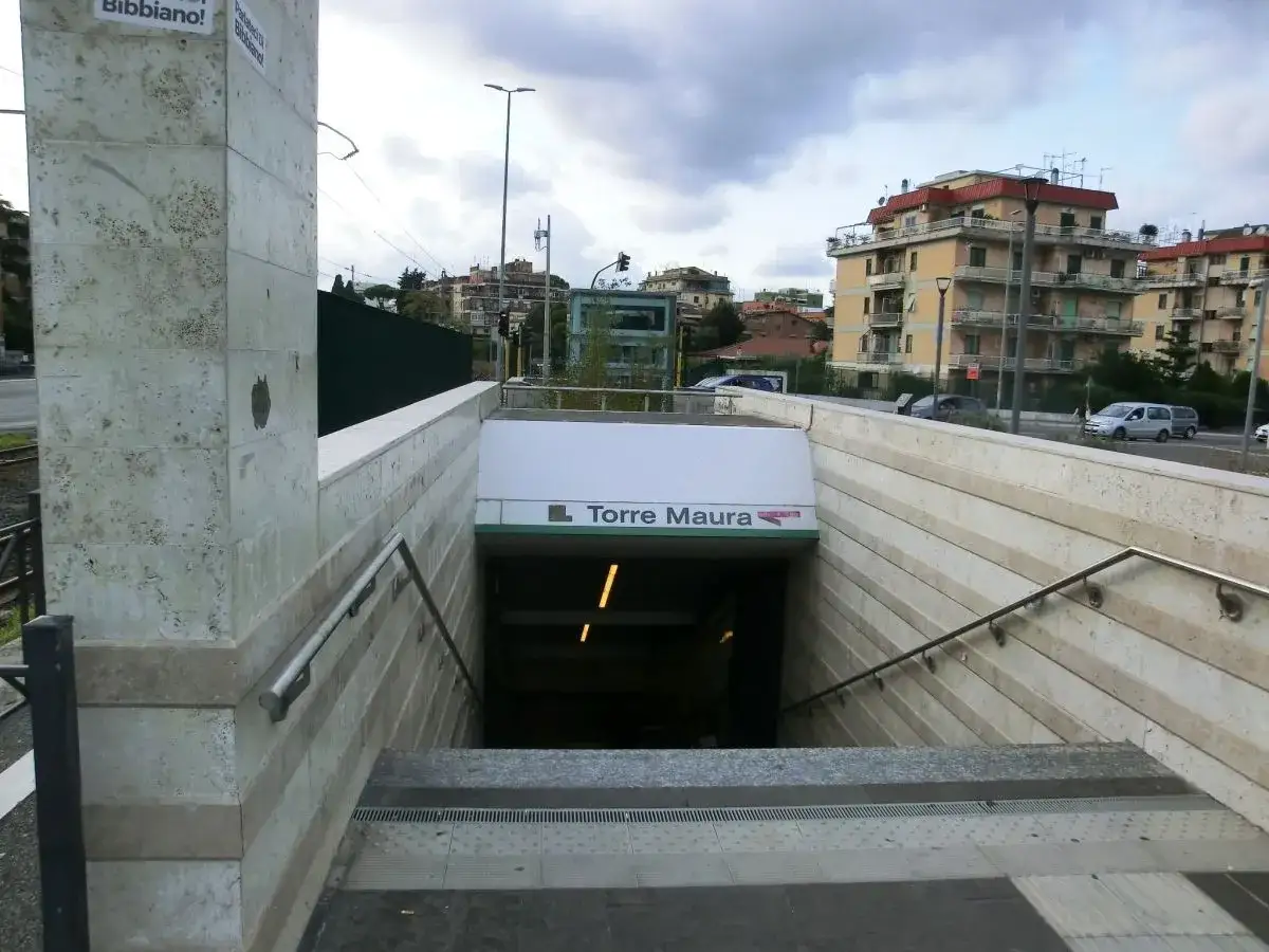 Ingresso della torre maura metro c, con scale che scendono nell'oscurità. Edifici residenziali sullo sfondo.