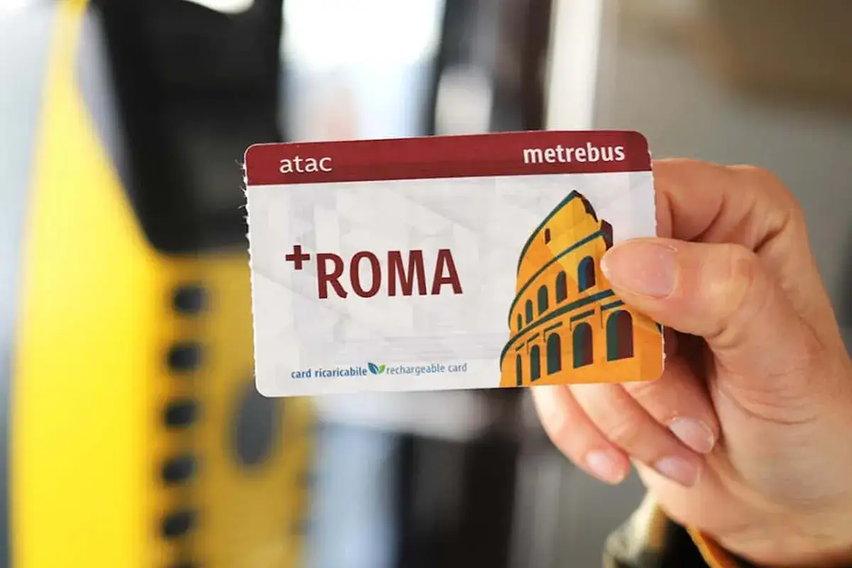 Una mano tiene una carta Metrebus ATAC con il Colosseo, pronta per un abbonamento metro Roma.