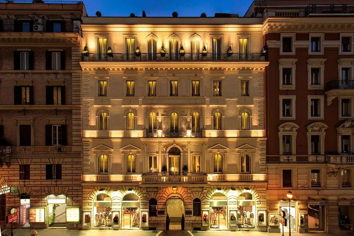 Edificio elegante illuminato di notte, con negozi al piano terra, nel quartiere Esquilino a Roma.
