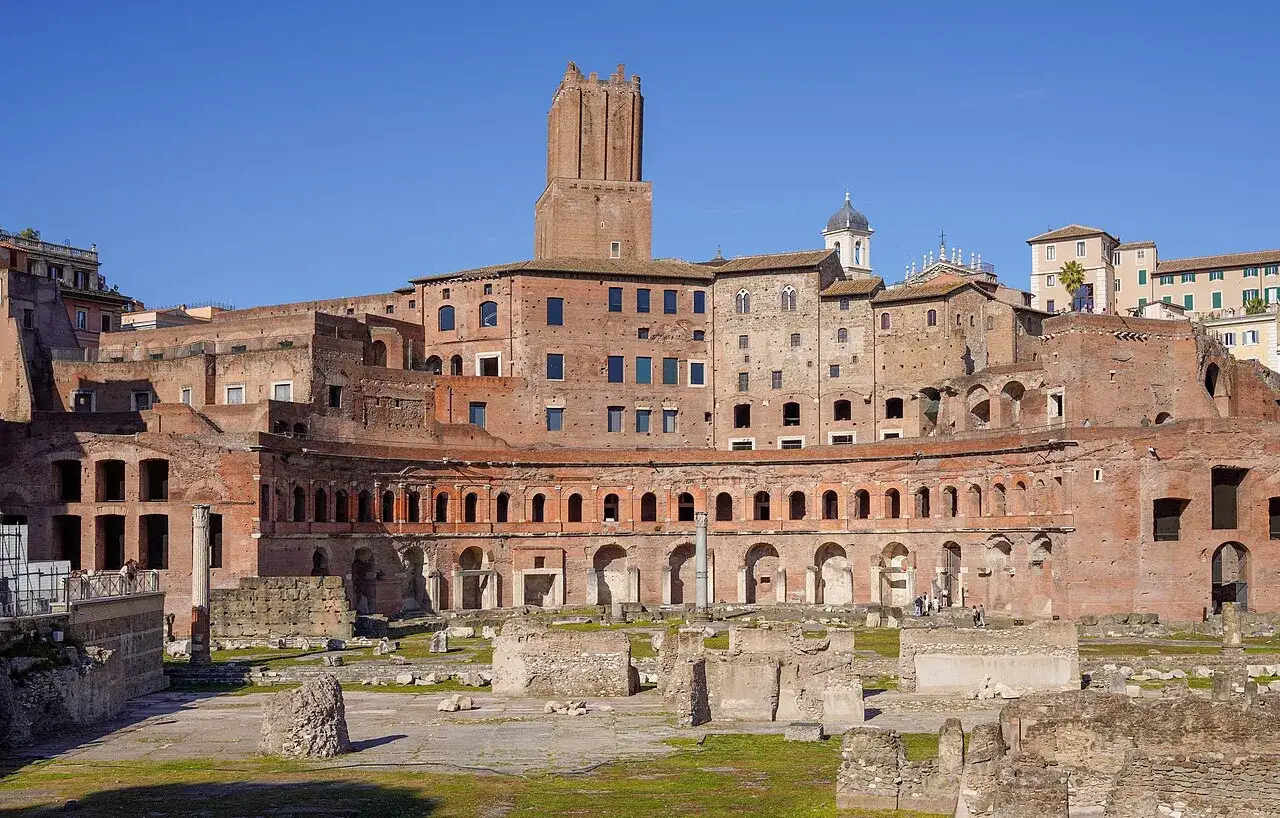 Antiche rovine del Mercado Trajano a Roma, con edifici in mattoni rossi e un cielo azzurro.