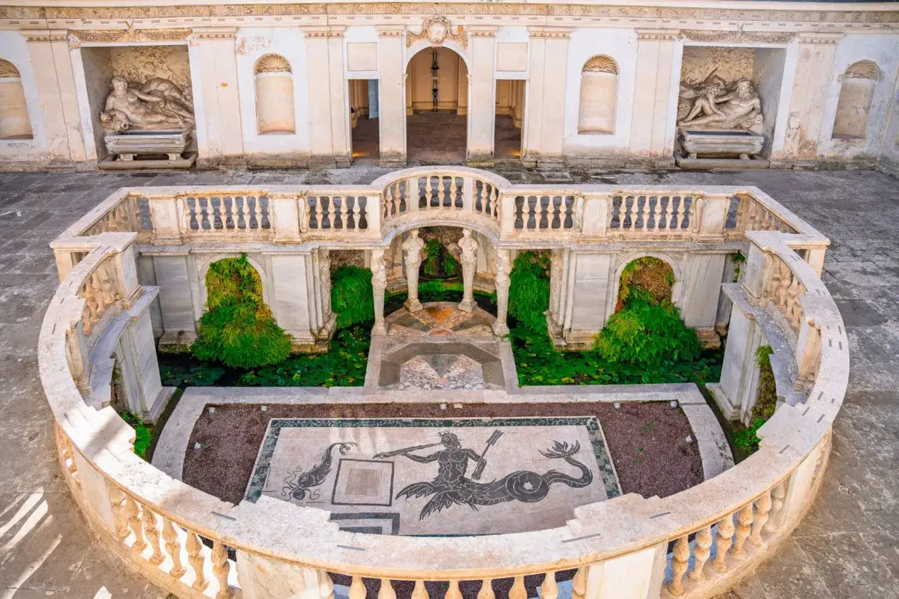 Cortile con fontana e mosaico marino a Villa Giulia, Roma. Statue classiche adornano le nicchie.